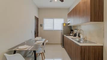 A modern kitchen with a dining area, wooden cabinets, a stainless steel sink, and a ceiling fan.