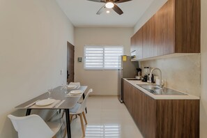 Una cocina moderna con comedor, armarios de madera, pileta de acero inoxidable y ventilador de techo.