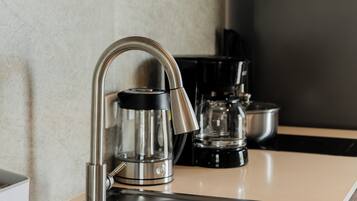 Cozinha equipada com uma pia de aço inoxidável, cafeteira e chaleira.