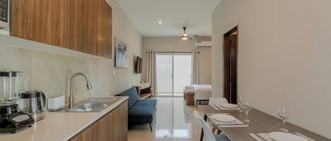A modern kitchen with a built-in island, a dining area with a table and chairs, and a view into a living space.