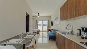 A modern kitchen with a dining area, a sofa, and a view to the outside.