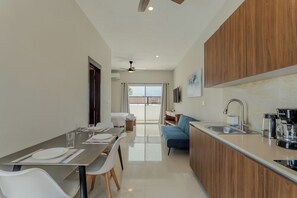 A modern kitchen with a dining area, a sofa, and a view to the outside.