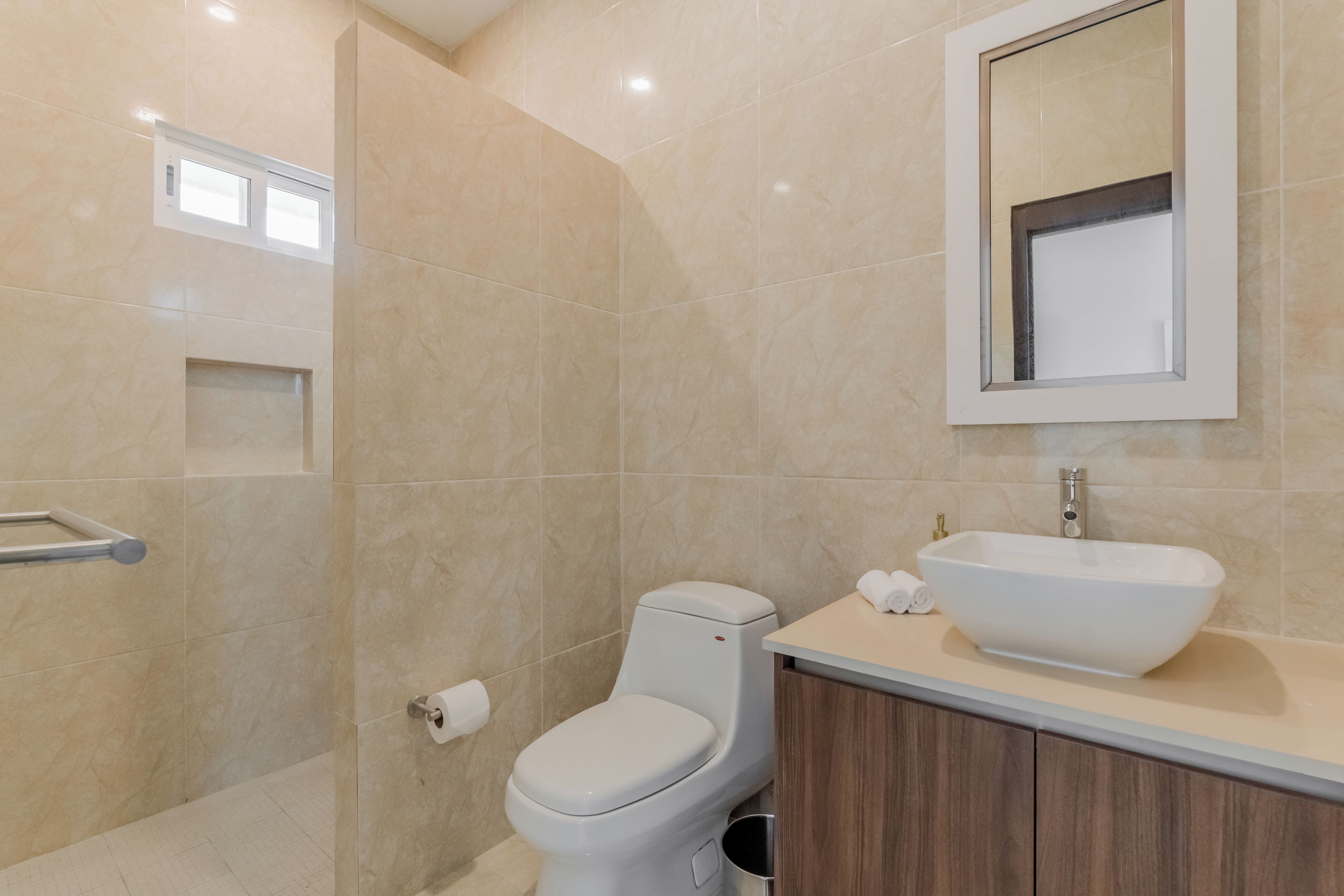 Un baño moderno con inodoro, lavabo y zona de ducha.
