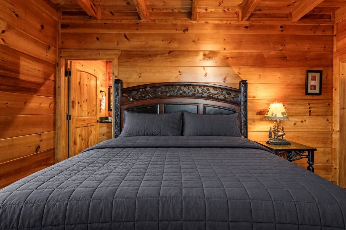 A wooden-paneled room with a bed, a nightstand, and a lamp.