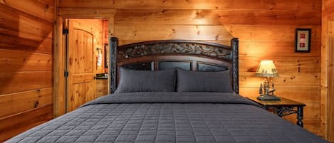 A wooden-paneled room with a bed, a nightstand, and a lamp.