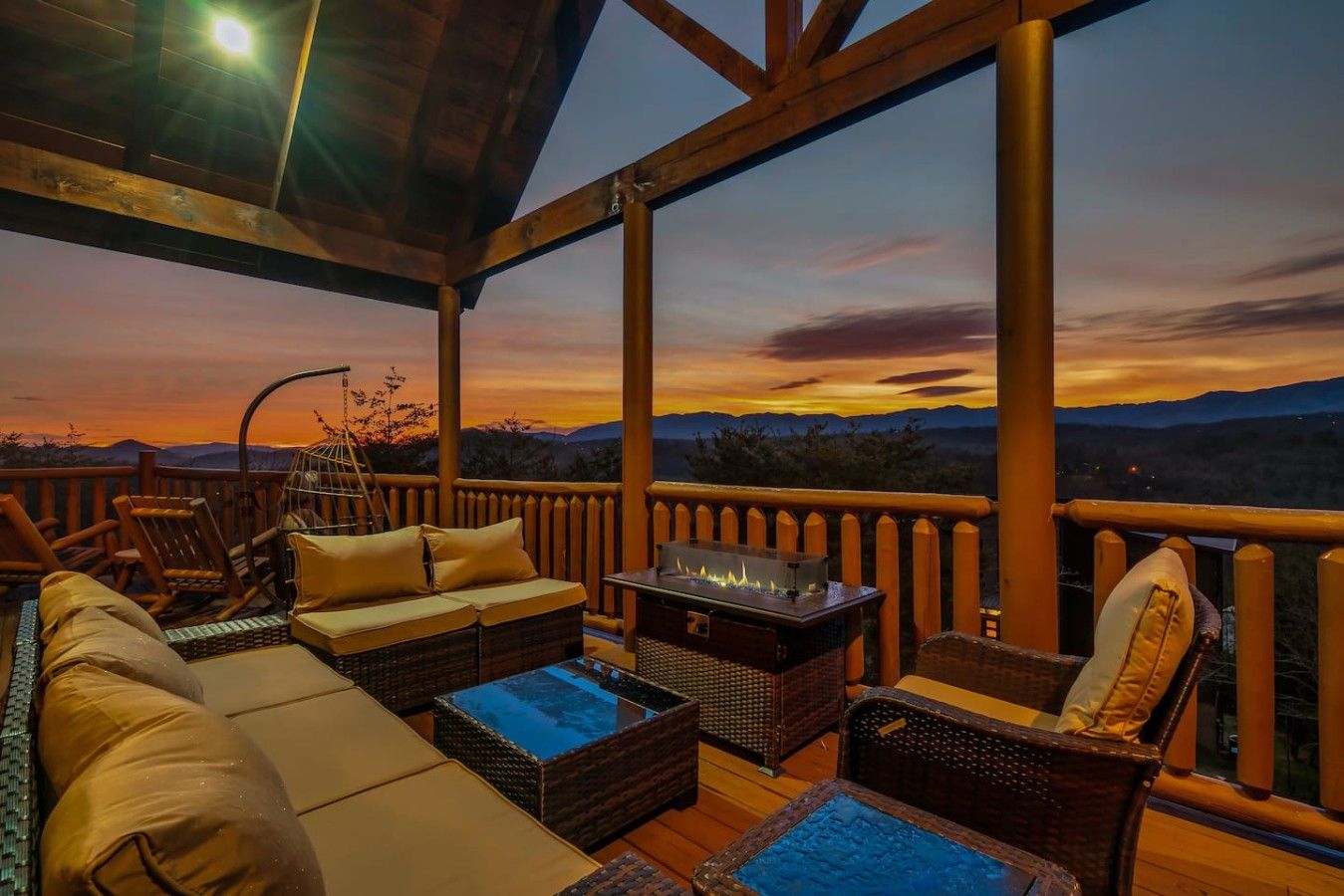 Une terrasse extérieure aménagée avec des meubles en osier, un foyer et une vue sur les montagnes.