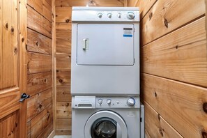 Eine kompakte, zweistöckige Waschküette mit einer Frontlader-Waschmaschine und einem Trockner, eingebettet in einen Raum mit Holzvertäfelung.