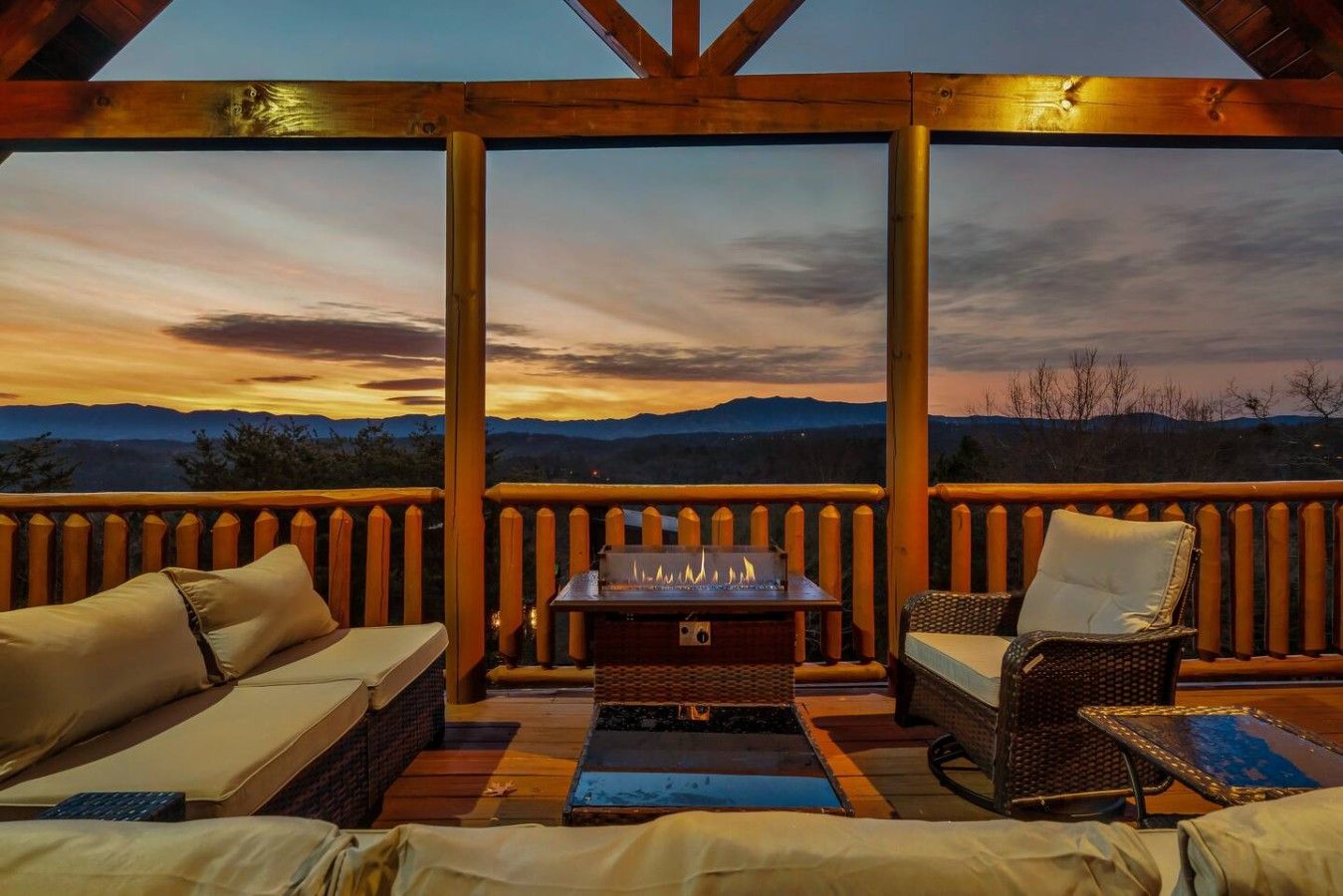 An outdoor deck with a fire pit, wicker furniture, and a view of the mountains.