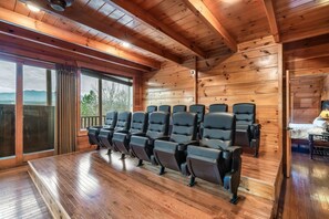 Ein Zimmer mit Holzboden, großen Fenstern und einer Sitzecke mit schwarzen Stühlen.