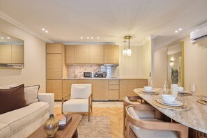 A modern kitchen with wooden cabinets, a marble countertop, and a dining area with a table set for two. - Elegant Apartment with AC - Center of Paris (Paris)