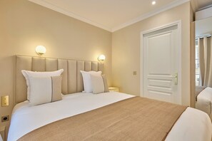 A hotel room with a large bed, two bedside tables, and a door with a handle. - Elegant Apartment with AC - Center of Paris (Paris)