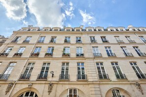 Un immeuble à plusieurs étages de style architectural classique, caractérisé par des fenêtres symétriques et des balcons ornés de rampes décoratives.