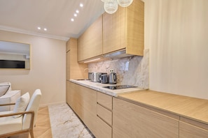 A modern kitchen with wooden cabinets, a marble countertop, and a built-in stove. - Elegant Apartment with AC - Center of Paris (Paris)