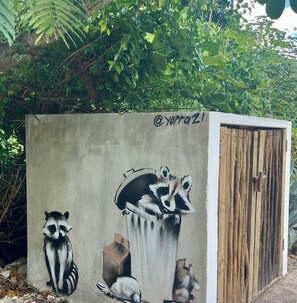 Una estructura de concreto con grafitis de mapaches y una puerta de madera.