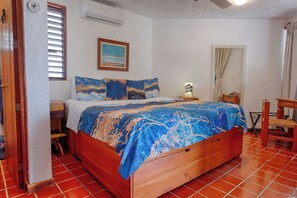 A bedroom with a wooden bed, a nightstand, a chair, a desk, and a window with blinds. - Villa Sunray. Entire 5 bedroom Villa with private pool and beach (Q.R.)