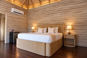 Ein Hotelzimmer mit einem großen Bett, zwei Nachttischen mit Lampen, einer Klimaanlage und Holzboden.