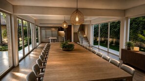 A modern dining area with a long wooden table, multiple chairs, and hanging pendant lights. - Miara Oasis - Celebrity Retreat in Casa de Campo (La Romana)