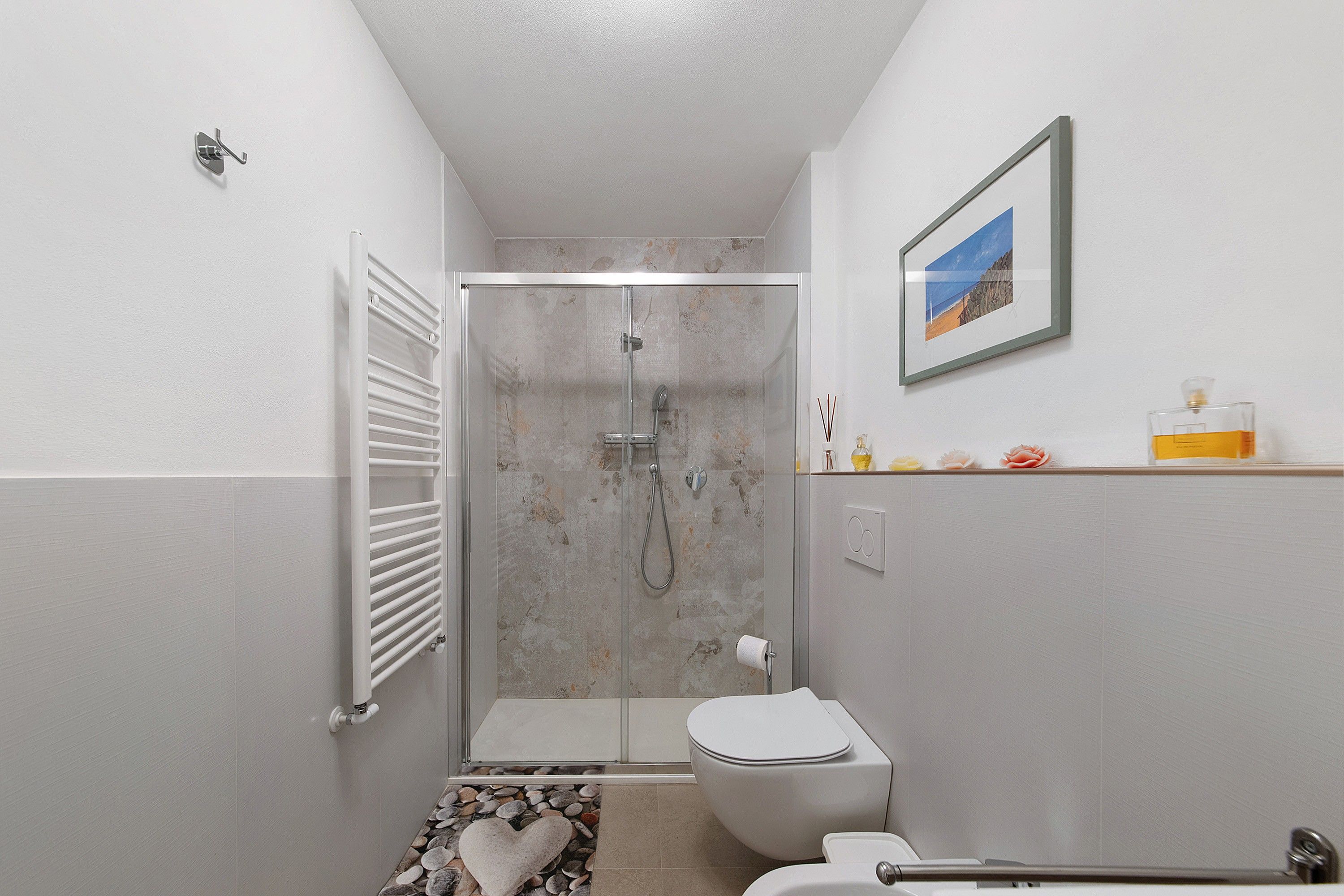 A bathroom with a glass-enclosed shower, a toilet, and a small shelf with toiletries.