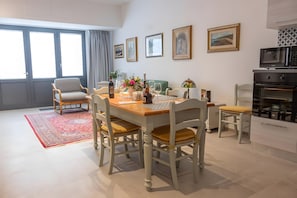 Un coin repas avec une table en bois, des chaises, un tapis rouge et des œuvres d’art accrochées aux murs.