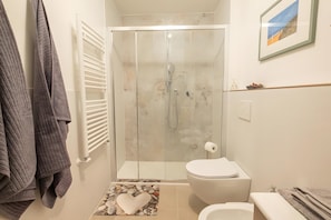 Une salle de bain avec une douche à parois de verre, des toilettes et un lavabo.