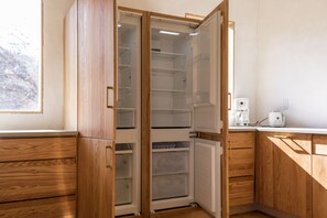 A kitchen with wooden cabinets, a built-in refrigerator, and a coffee maker on the countertop.