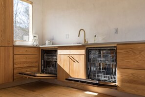 Cuina moderna amb armaris de fusta, rentaplats integrat i campana extractora d'acer inoxidable.