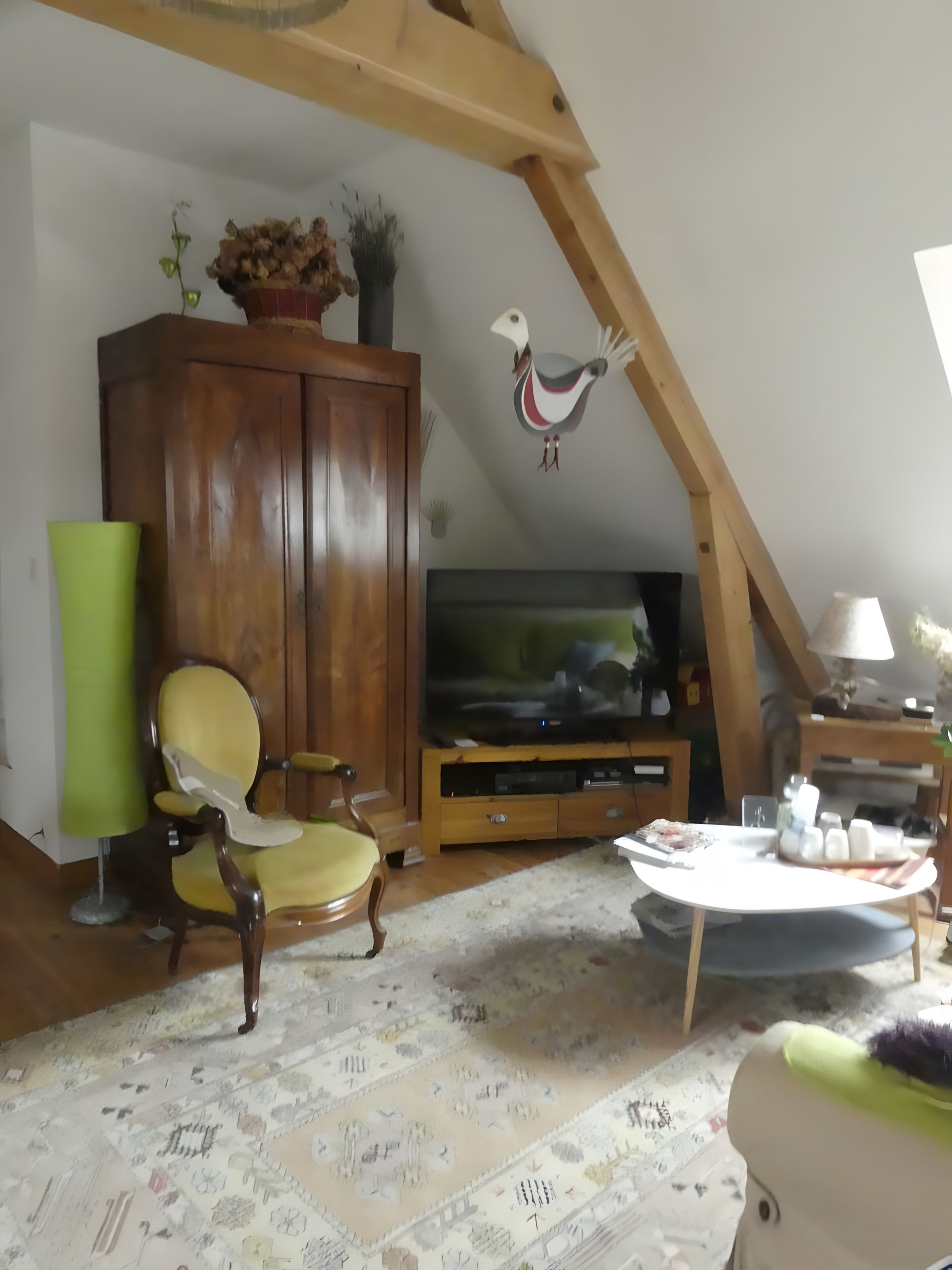 Een woonkamer met een houten kast, een televisie, een groene lamp, een kamerkleed met een patroon en een decoratieve wandversiering.