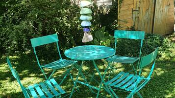 A small outdoor seating area with a round table and two chairs, surrounded by greenery.