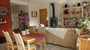 Una sala acogedora con sofá, mesa de comedor y sillas, estantería y chimenea.