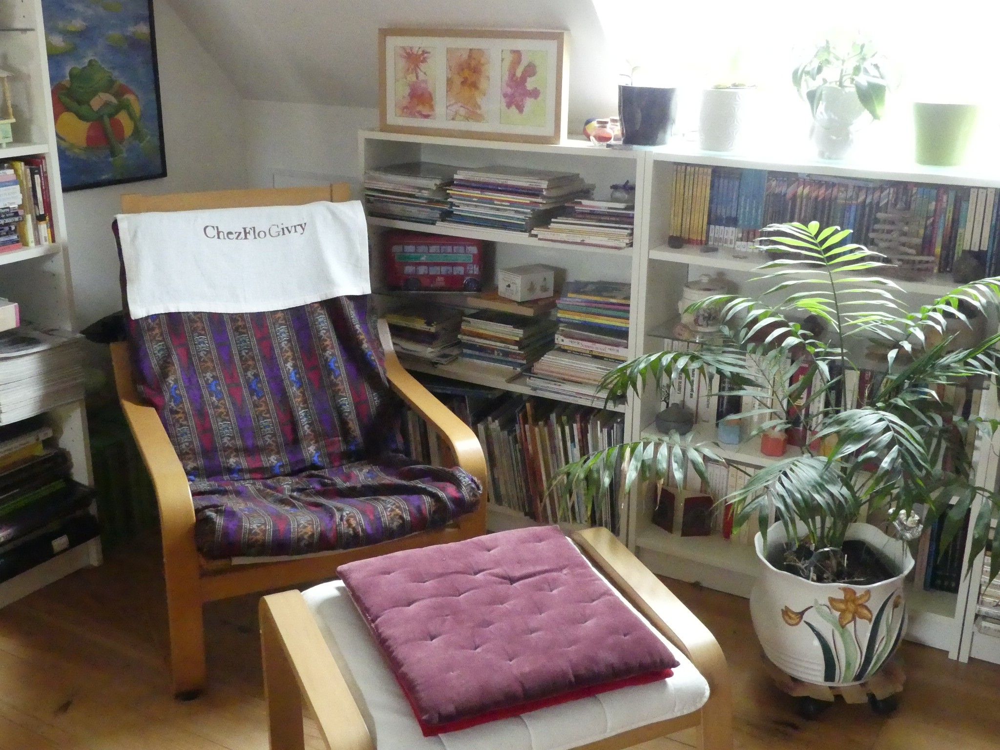 Een leeshoekje met een fauteuil, een tafeltje en een boekenplank vol boeken.