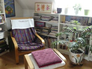 Eine Leseecke mit einem Sessel, einem kleinen Tisch und einem Bücherregal voller Bücher.