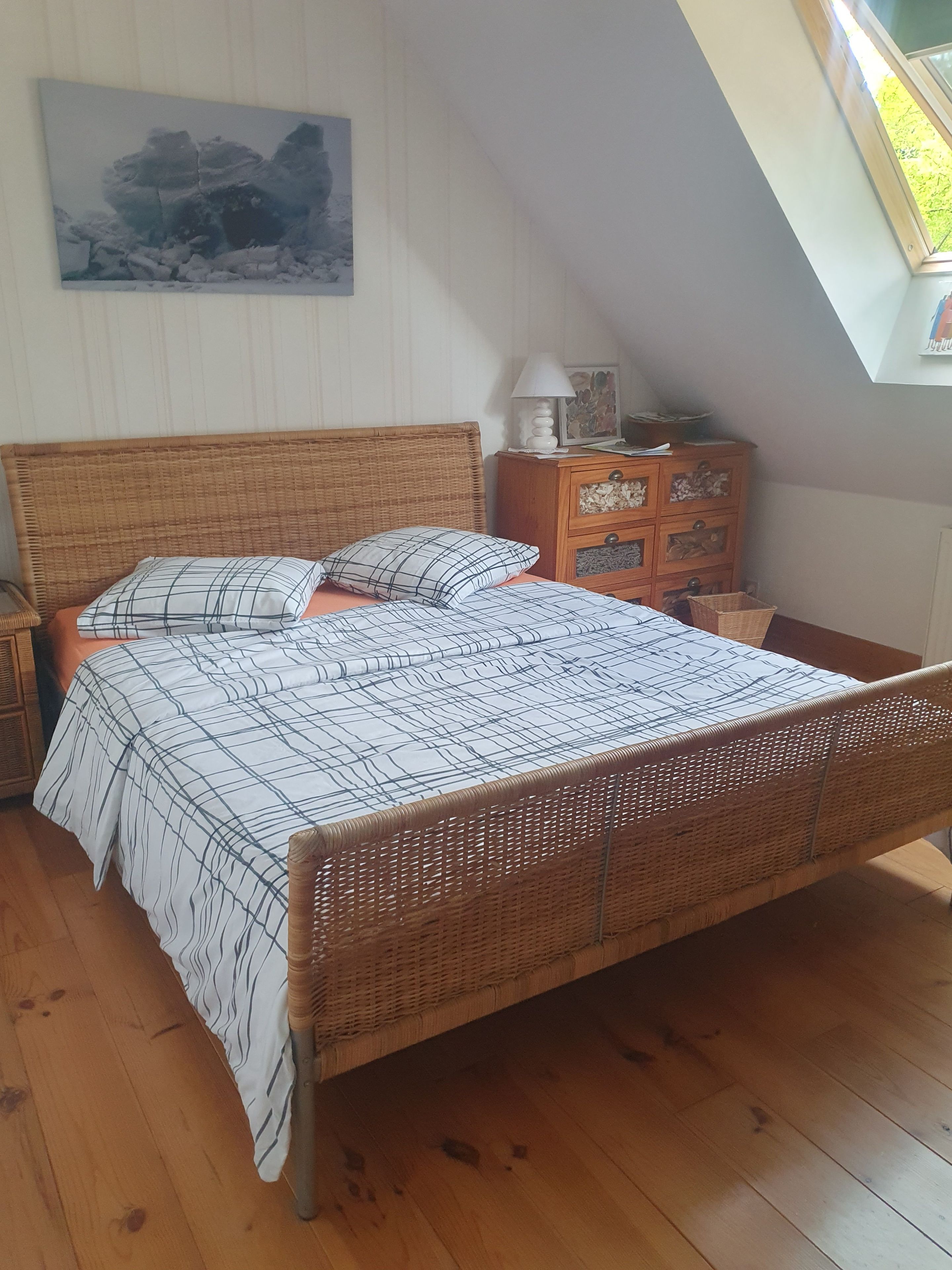 Une pièce comprenant un lit, une table de chevet, une commode et un tableau accroché au mur.