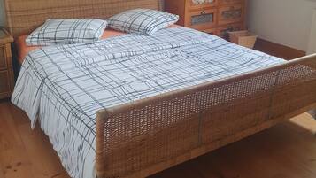 Een kamer met een bed, nachtkastje, dressoir en een schilderij aan de muur.