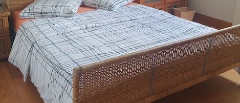 Une pièce comprenant un lit, une table de chevet, une commode et un tableau accroché au mur.