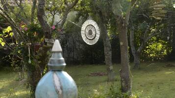 Un giardino con una vasca per uccelli e una scultura circolare in metallo.