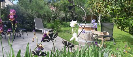 A garden patio with outdoor furniture, a wooden barrel, and various plants.
