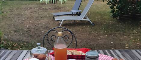 A picnic setup with a checkered tablecloth, various food items, condiments, and a bottle of iced tea.