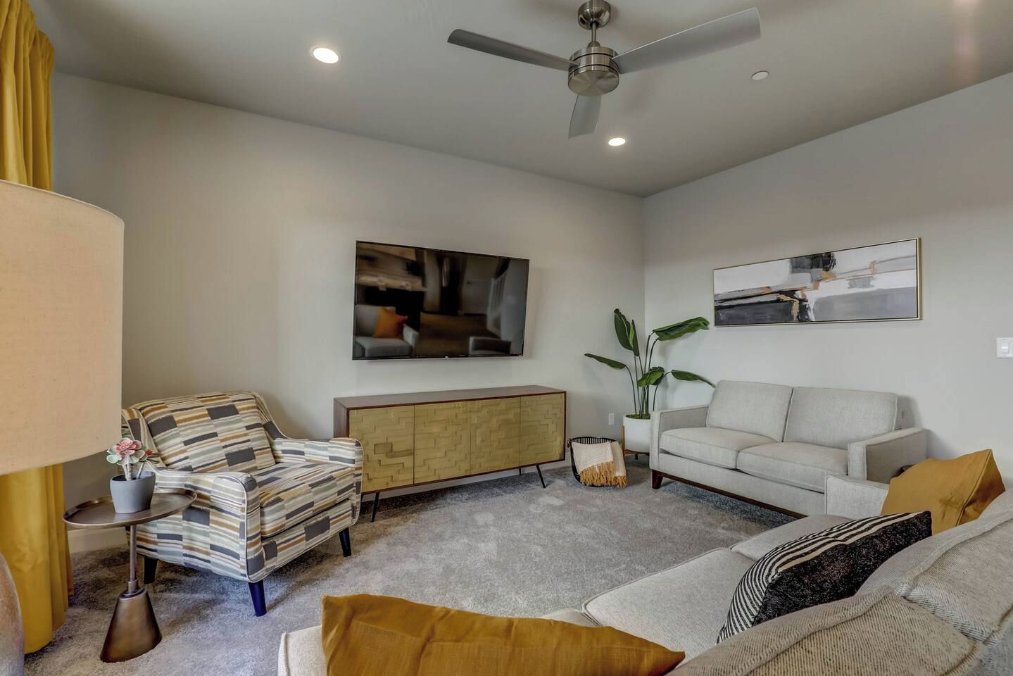 A living room with a sofa, armchair, and a ceiling fan.