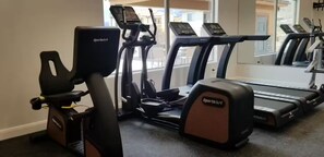 Ett gym med konditionsutrustning, inklusive en motionscykel, en crosstrainer och löpband.