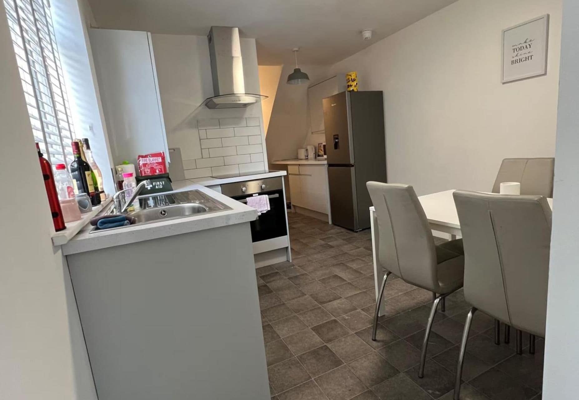 A compact kitchen with a sink, stove, and a small dining area with chairs.