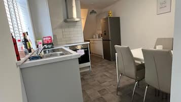 A compact kitchen with a sink, stove, and a small dining area with chairs.