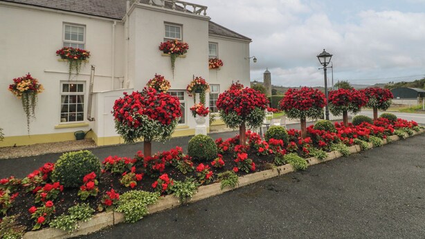 A white building with multiple flower boxes on the windowsills, a paved driveway, and a clear sky. - Bruckless Rest Fine Country Living B&amp;b (Bruckless)