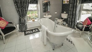 A bathroom with a freestanding bathtub, a sink, and a toilet. There is a window with a view of greenery outside. - Bruckless Rest Fine Country Living B&amp;b (Bruckless)