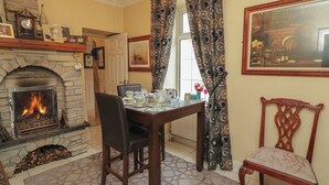 A cozy room with a stone fireplace, a dining table set with china, and a decorative chair. - Bruckless Rest Fine Country Living B&amp;b (Bruckless)