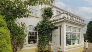 A white building with a conservatory, surrounded by greenery and gravel. - Bruckless Rest Fine Country Living B&amp;b (Bruckless)