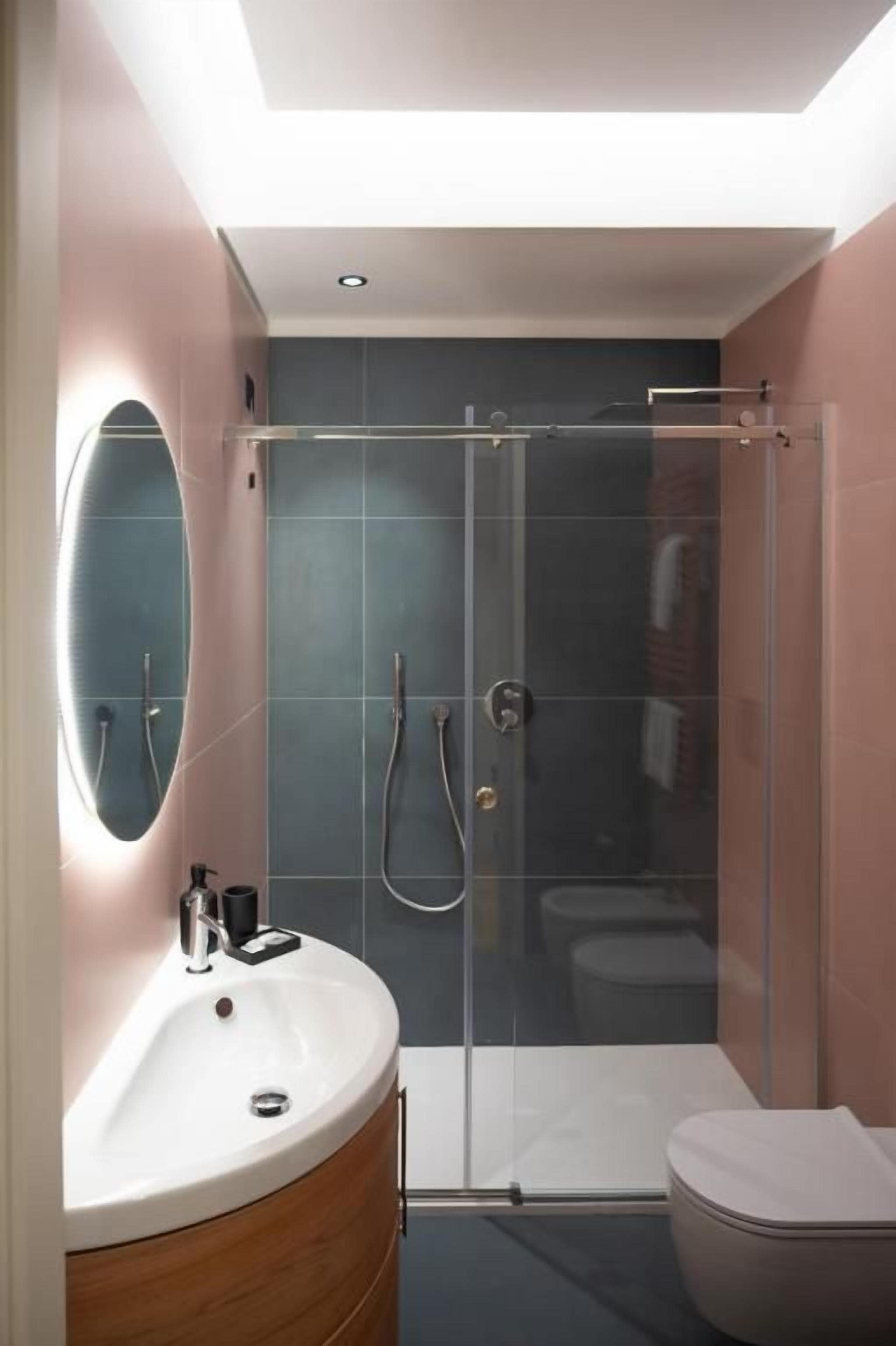 Un baño moderno con ducha de vidrio, tocador con espejo y retrete.
