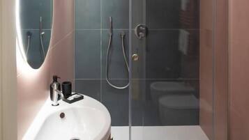 Un baño moderno con ducha de vidrio, tocador con espejo y retrete.