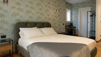 A bedroom with a large bed, a bedside table, a wardrobe, and a window.
