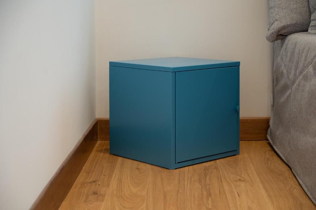 Un mueble pequeño color turquesa en una esquina de una habitación con suelo de madera.