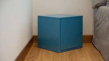 Un mueble pequeño color turquesa en una esquina de una habitación con suelo de madera.
